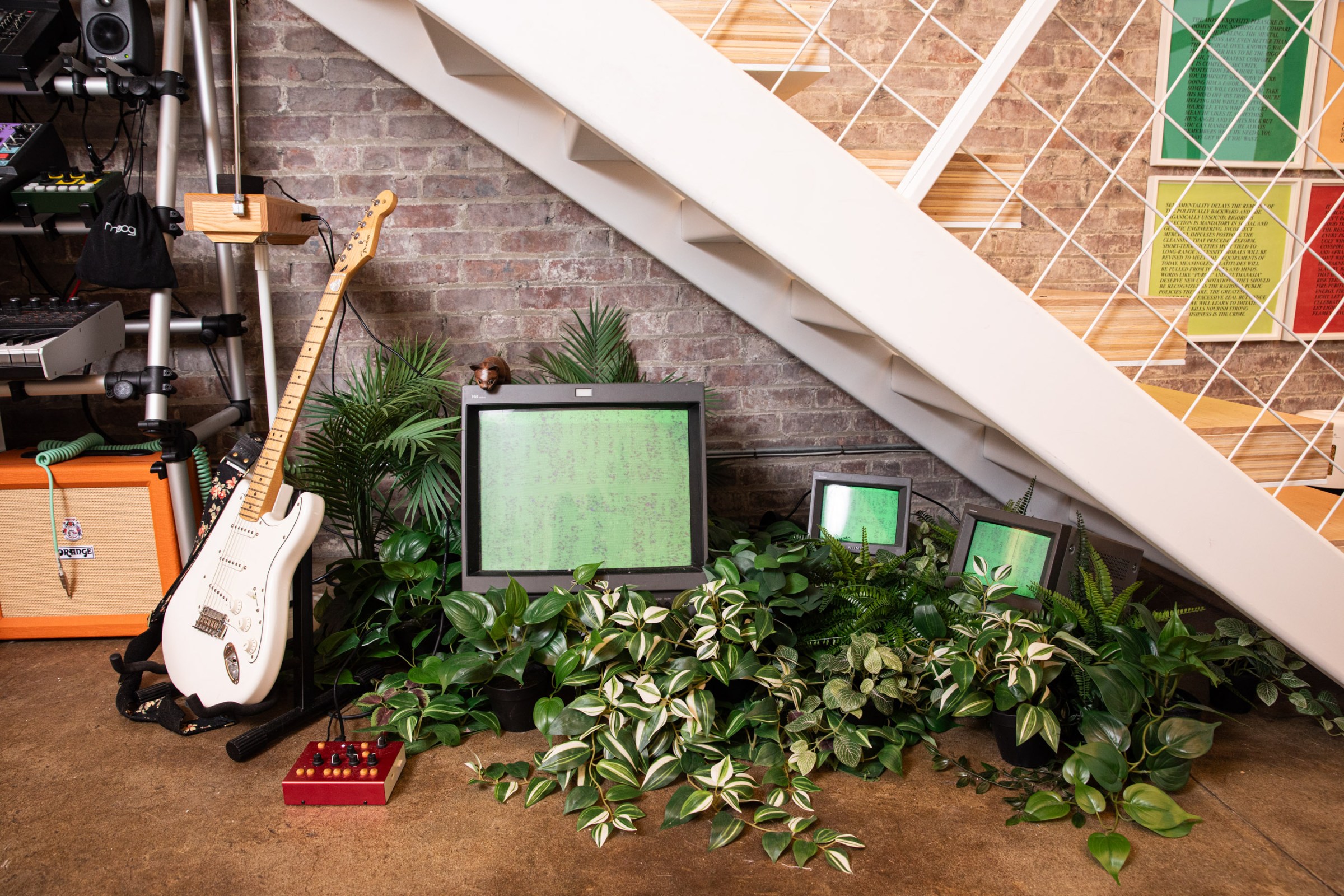 An homage to Nam June Paik’s “TV Garden” sits under the stairs at the edge of the living room. Images on the CRT TVs are responsive to the sounds created at the console to its left.