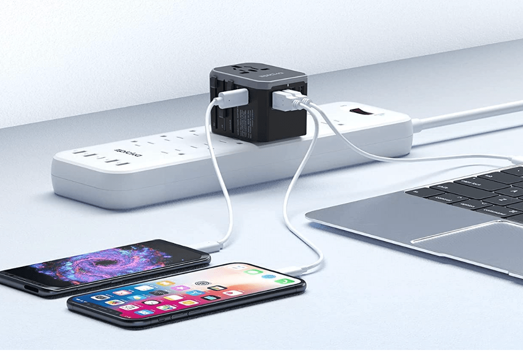 Travel adaptor on power strip connected to phones and laptop.