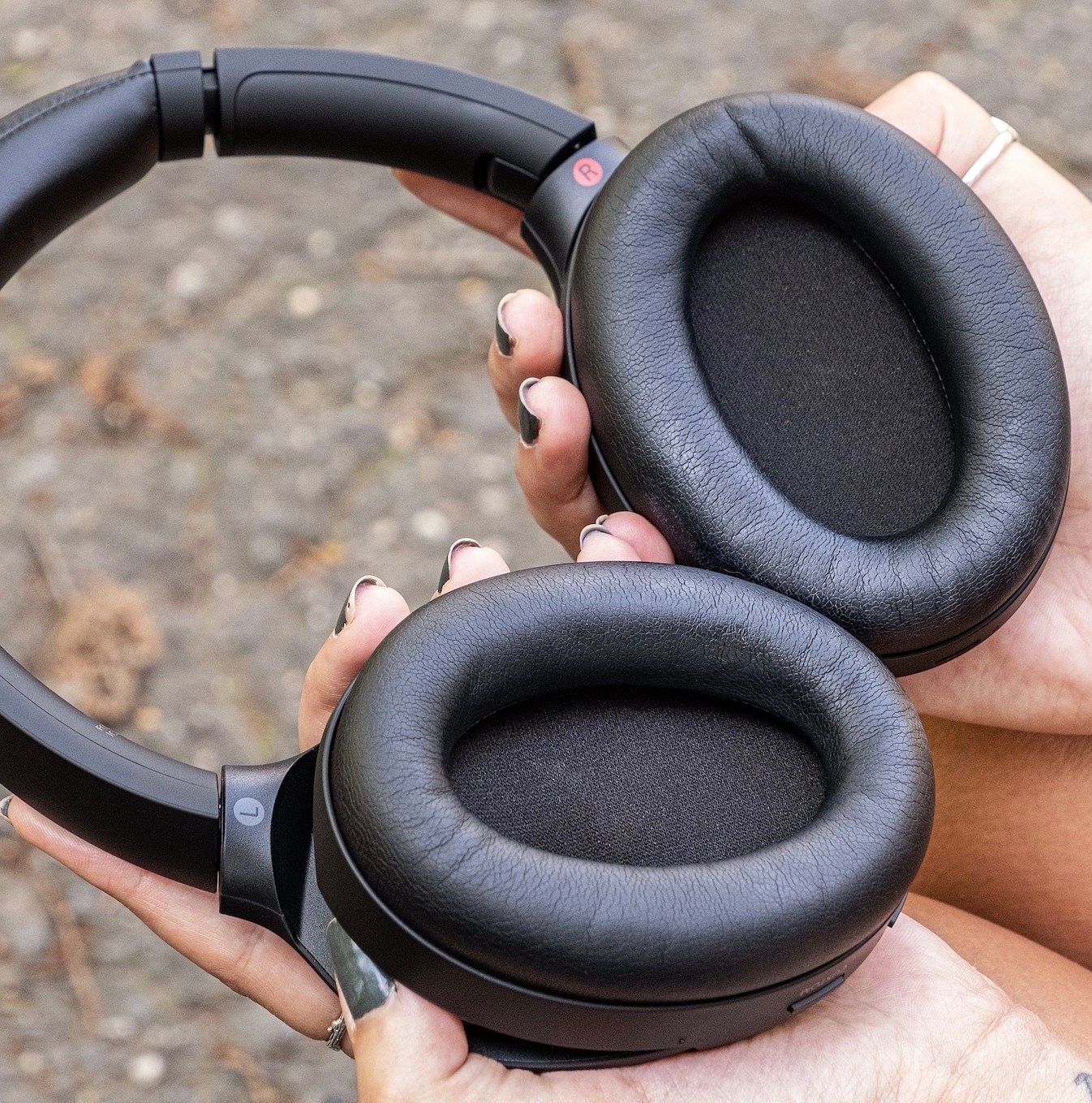 A person holding a pair of Sony WH-1000XM4 headphones.