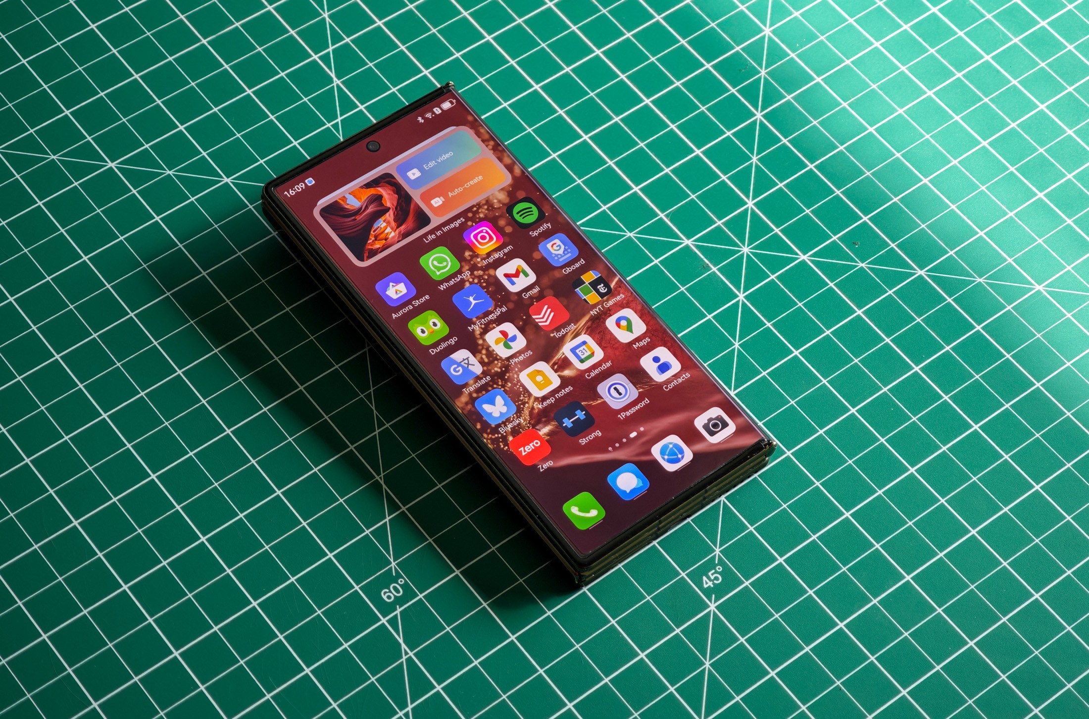Huawei Mate XT flat on a green table folded.