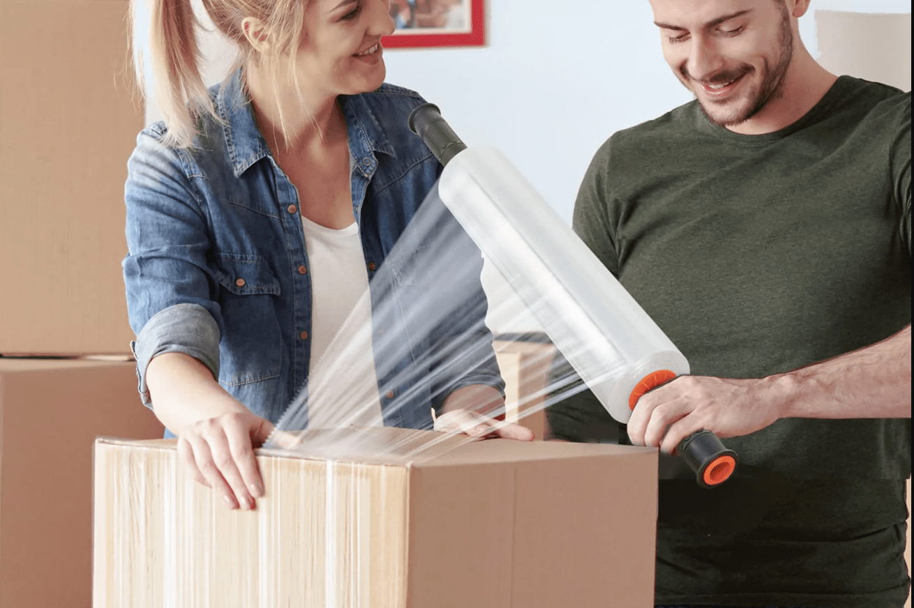 Man and woman with roll of shrink wrap covering a box.
