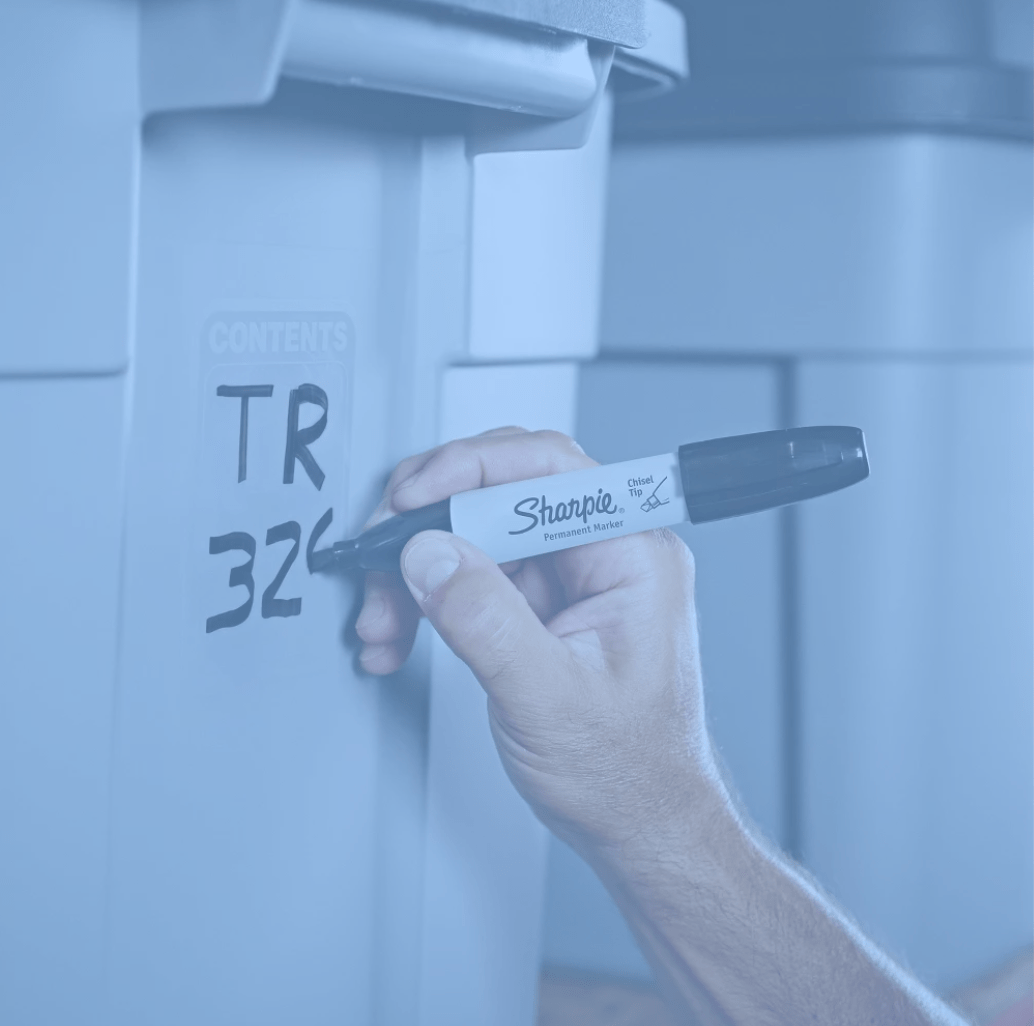 Hand using a sharpie pen to write on a bin.