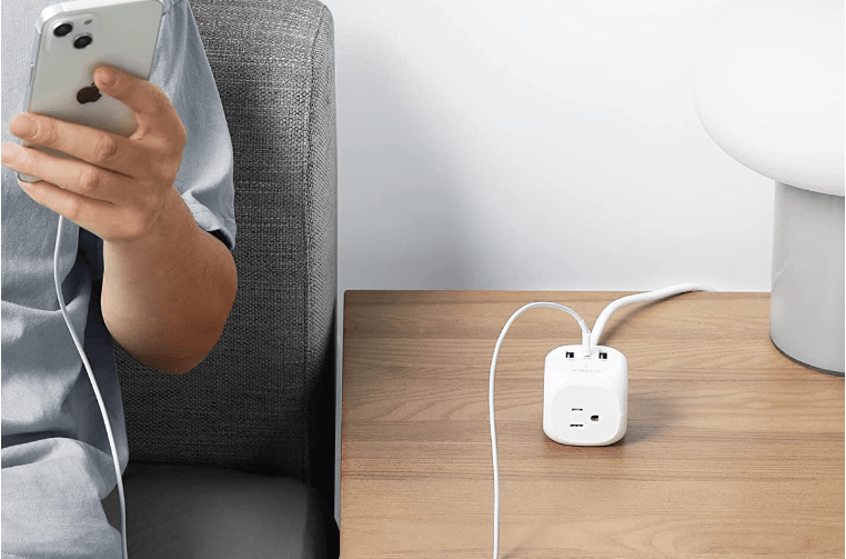 Anker cube power strip on table in between a person with a phone and a computer