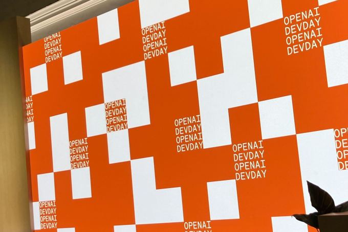The OpenAI logo on screen at their developer day stage.