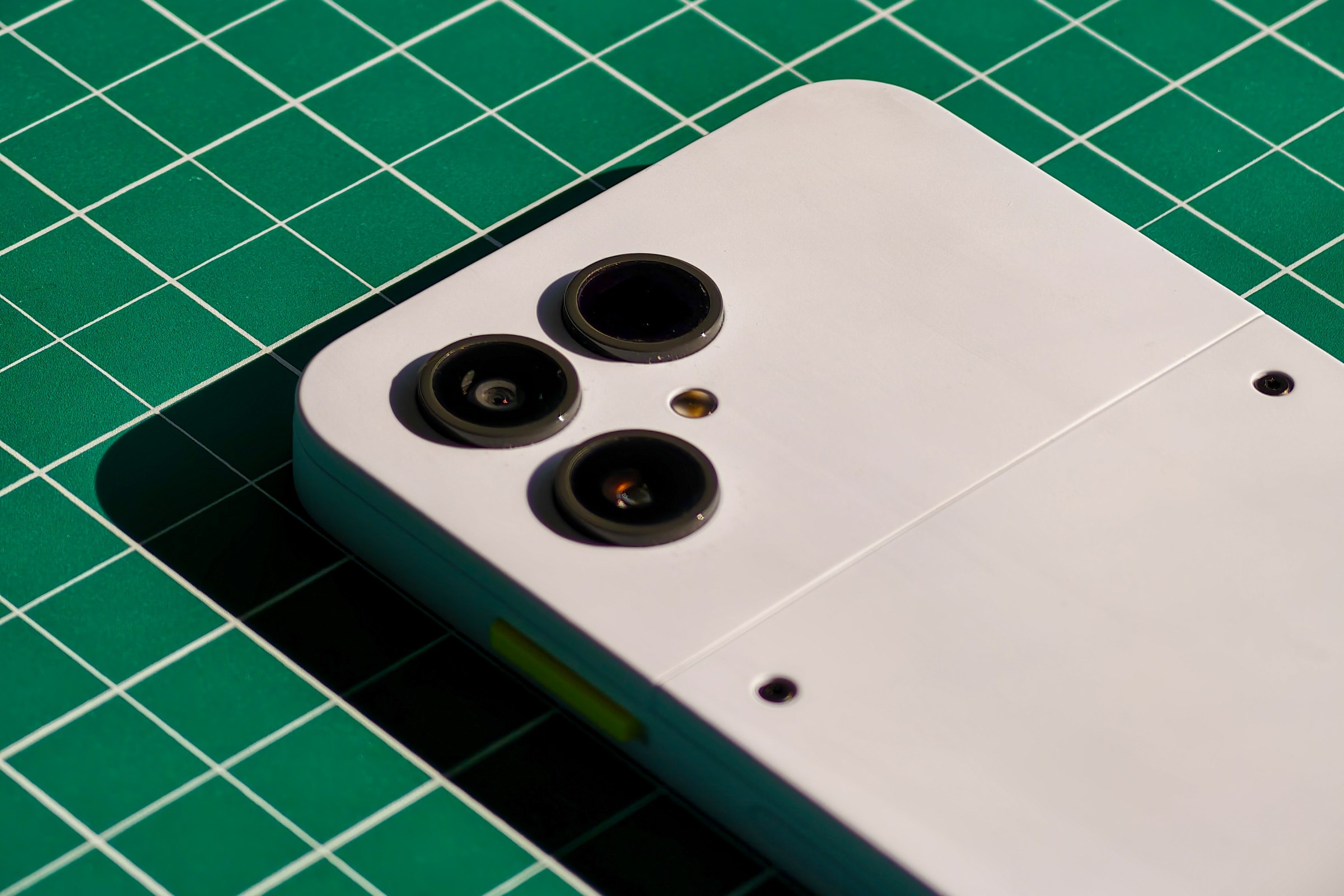 Photo of the Fairphone 6 lying on a green cutting mat with a closeup on the camera