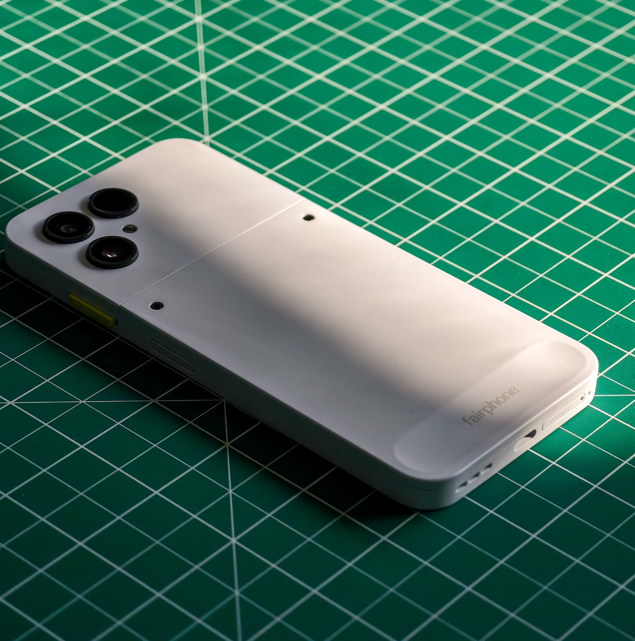 Photo of the Fairphone 6 lying on a green cutting mat
