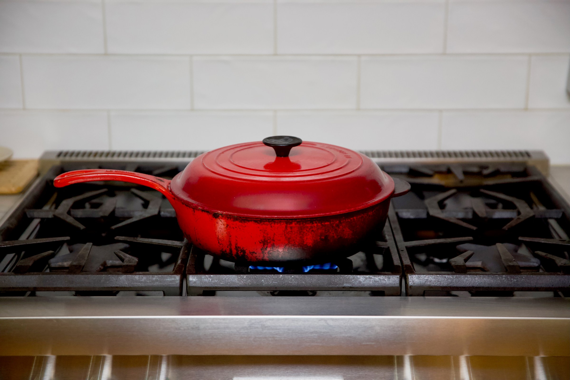 A red pot with black markings on the sides on a stove