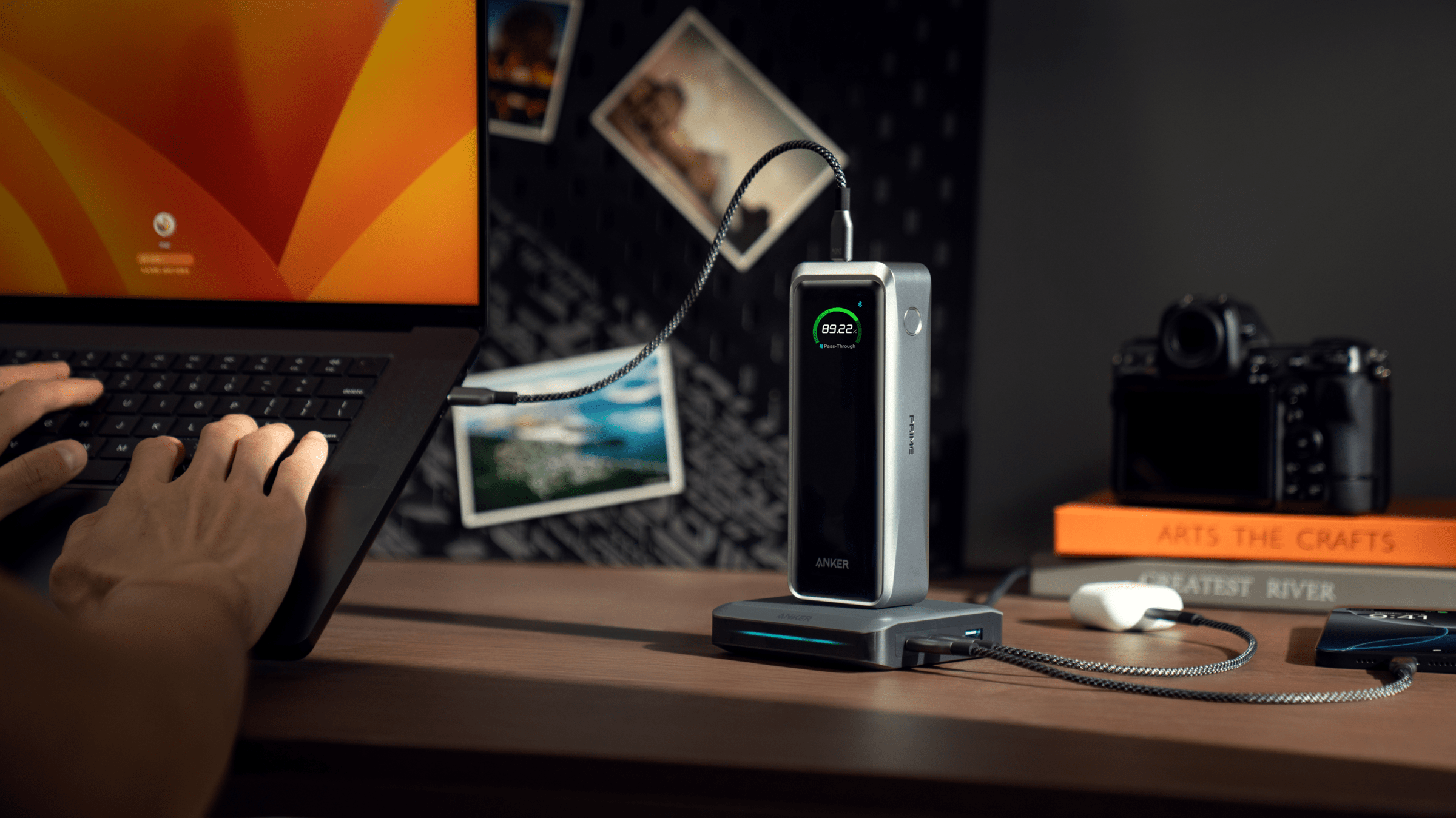 Anker’s new Prime Power Bank sitting on its charging dock on a desk and connected to a laptop.