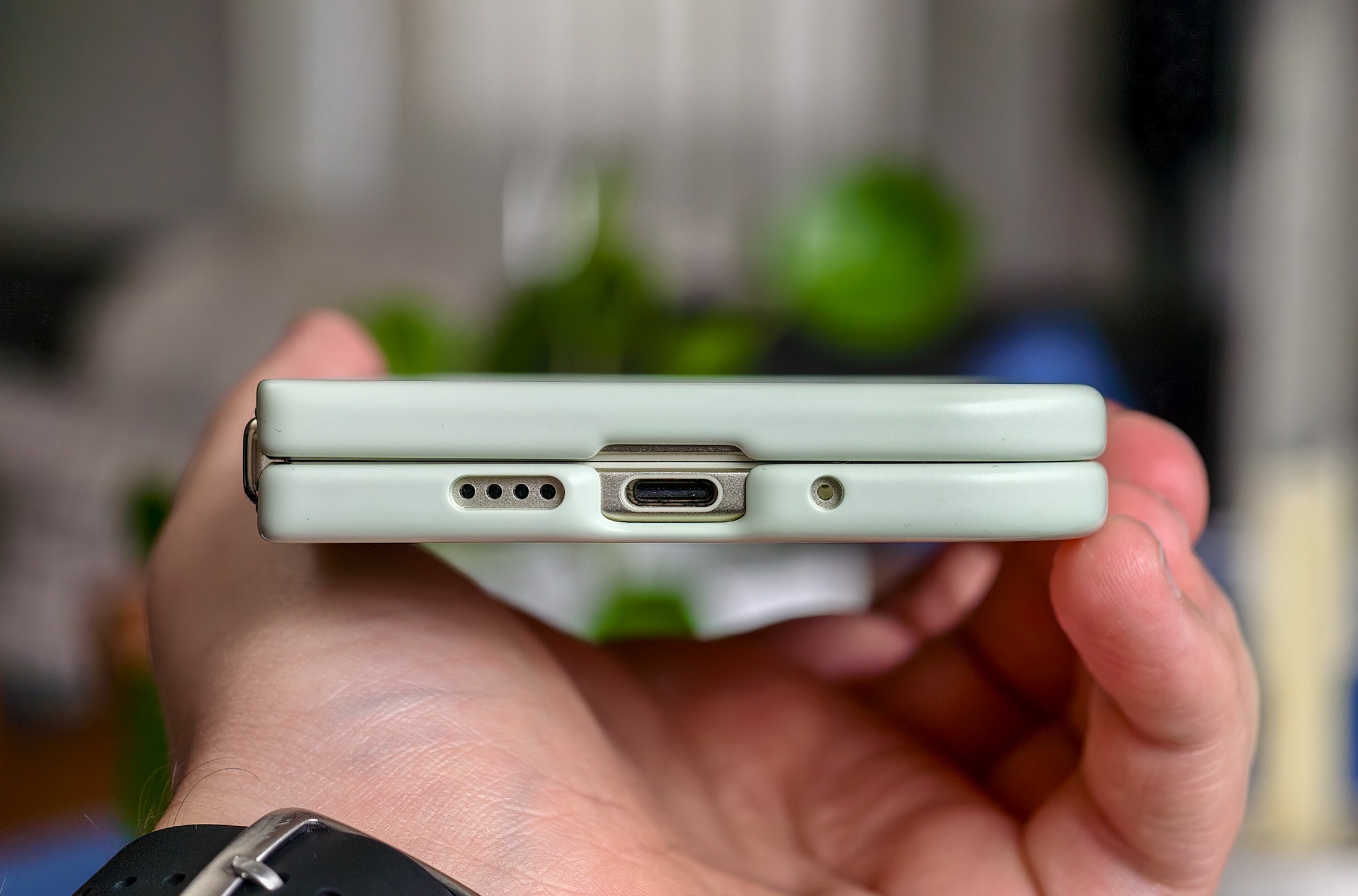 Google Pixel 10 Pro Fold held in a hand, horizontal and closed in the Pixelsnap case, showing the phone’s thin edge