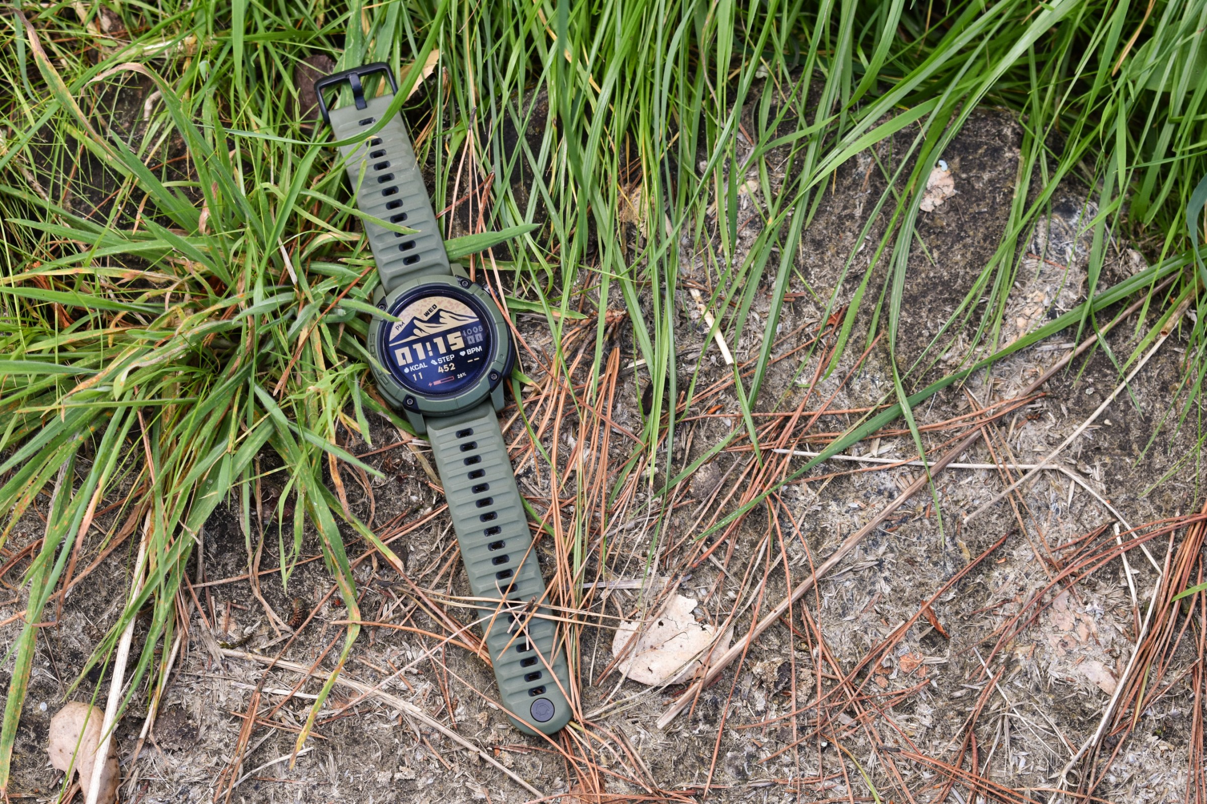 A Coros Nomad watch, positioned in some green grass.